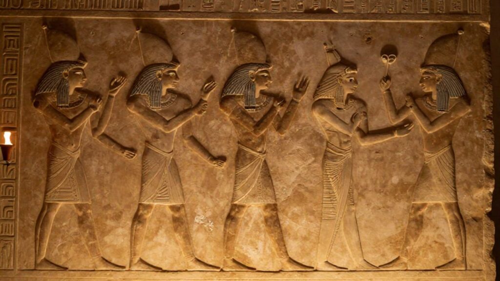 Relieve en piedra caliza de bailarinas egipcias con vestimentas ceremoniales y gestos rítmicos.